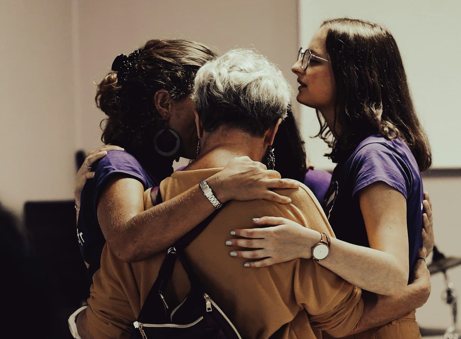 Friends holding an older woman in a supportive group hug